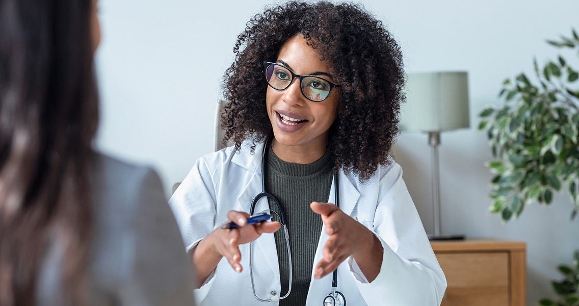 Doctor talking with patient at desk Doctor facing patient/camera talking at a desk smiling