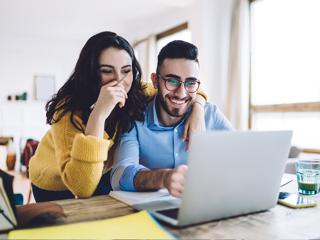 Happy Couple Looking at a Laptop 